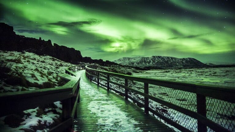 Northern Lights Above Þingvellir National Park: A dramatic scene of the Northern Lights shining over Þingvellir National Park in Iceland. The aurora's vibrant colors illuminate the unique geological formations and vast landscape below.